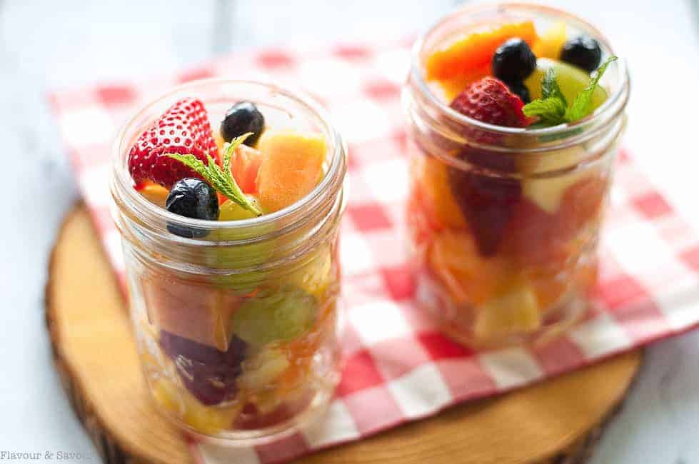 Mason Jar Boozy Tropical Fruit Salad in two jars on a checkered cloth 