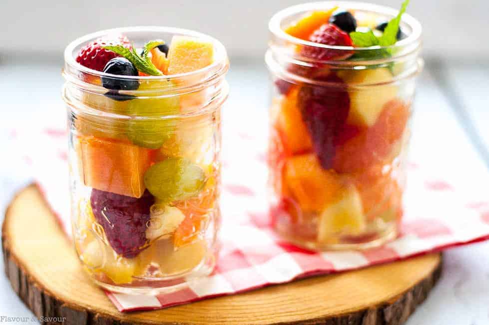 Mason Jar Boozy Tropical Fruit Salad in jars on a serving board