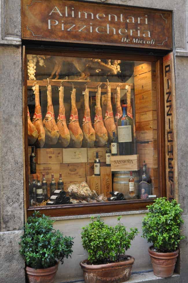 Prosciutto hams hanging in a store window in Italy.