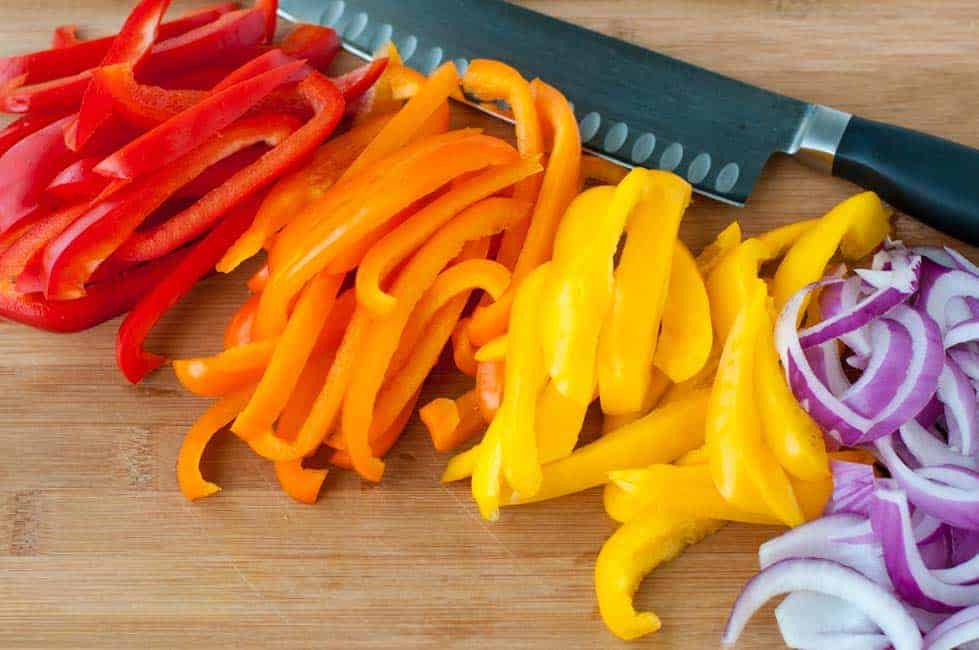 Slicing tri-coloured peppers and red onions for Easy Chicken Fajitas in Foil Packets