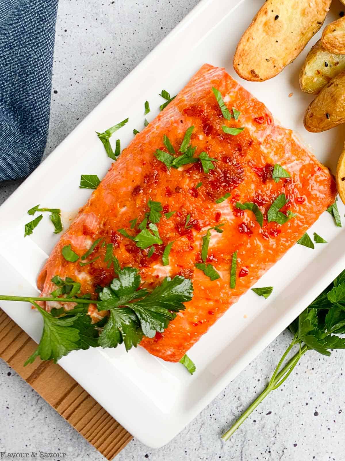 Close up view of Citrus Chardonnay Glazed Salmon on a platter with parsley