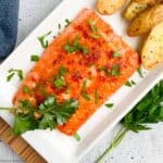 Honey Citrus Glazed Salmon filet on a white platter with air-fried potatoes.