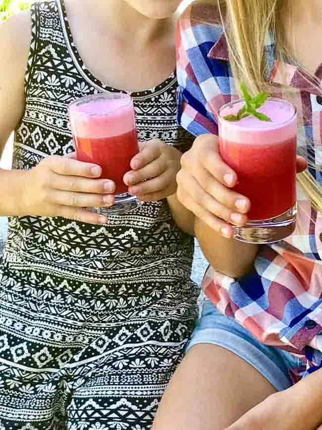two girls with glasses of Wild Huckleberry Mint Mohito Mocktail