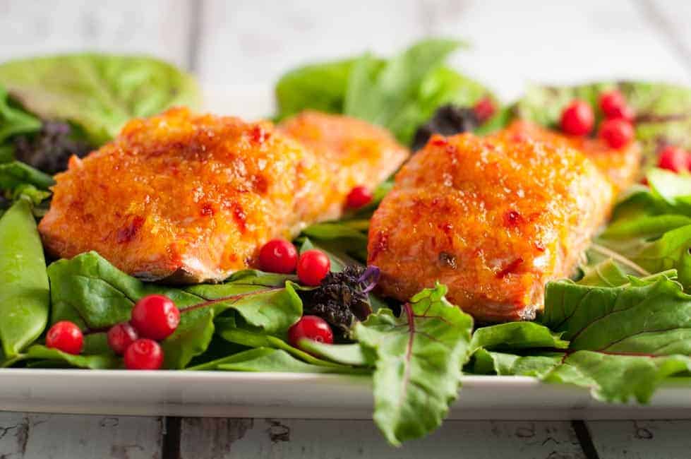 Side view of two fillets of honey citrus glazed salmon on a bed of greens.