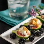 A tray of fresh figs with goat cheese and maple walnuts served with fresh blackberries.