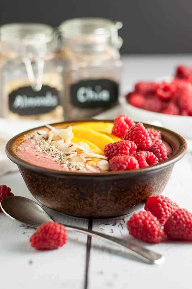 Healthy Peach Melba Breakfast Smoothie Bowl garnished with peaches, raspberries, sliced almonds and hemp seeds.