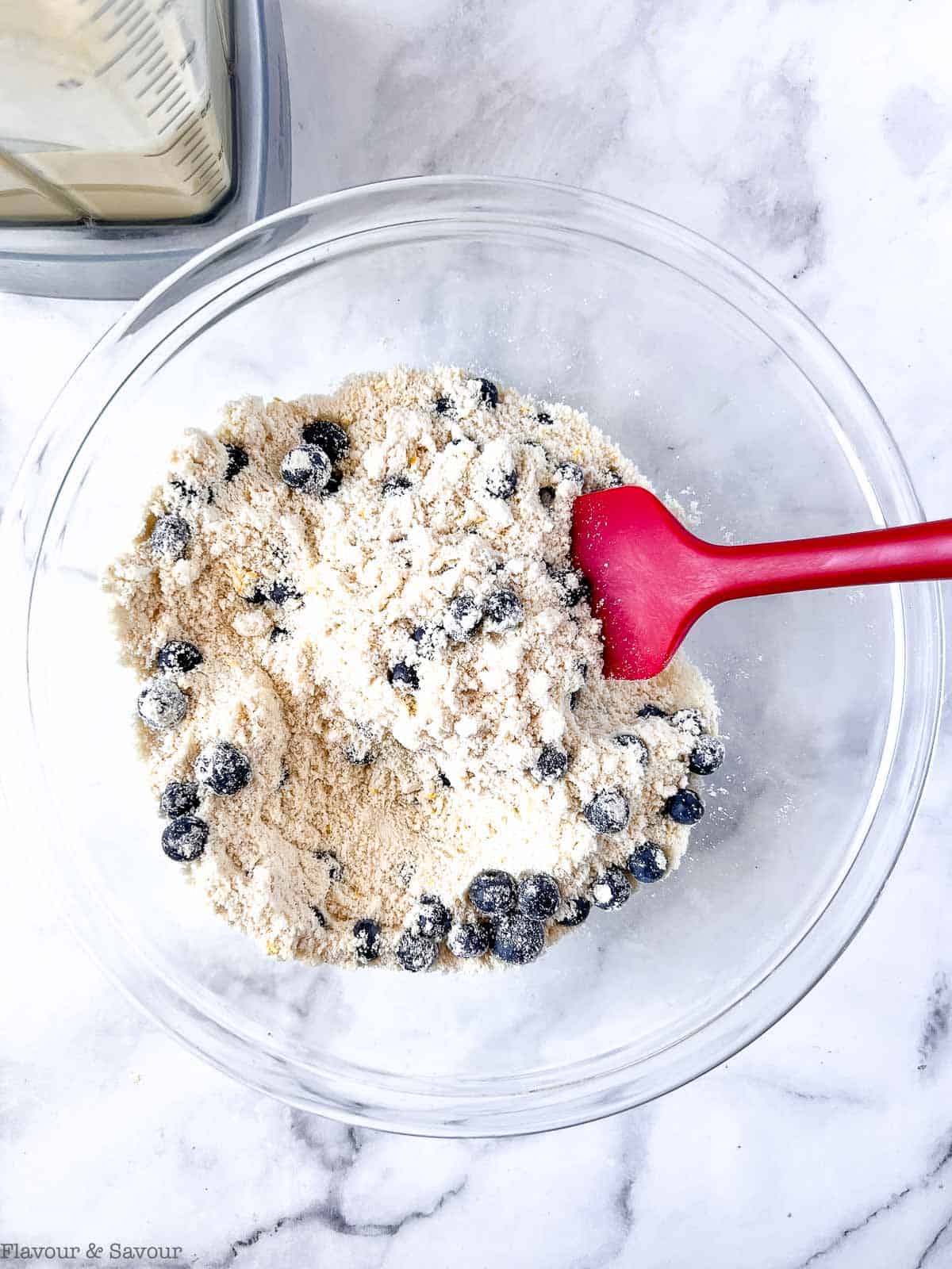 Adding blueberries to blueberry lemon coffee cake dry ingredients.