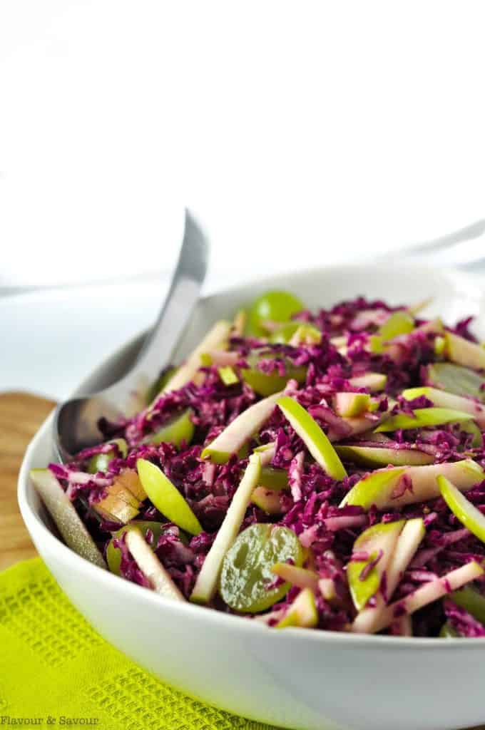 Side view of Grape Apple and Red Cabbage Slaw in a white bowl on a green cloth