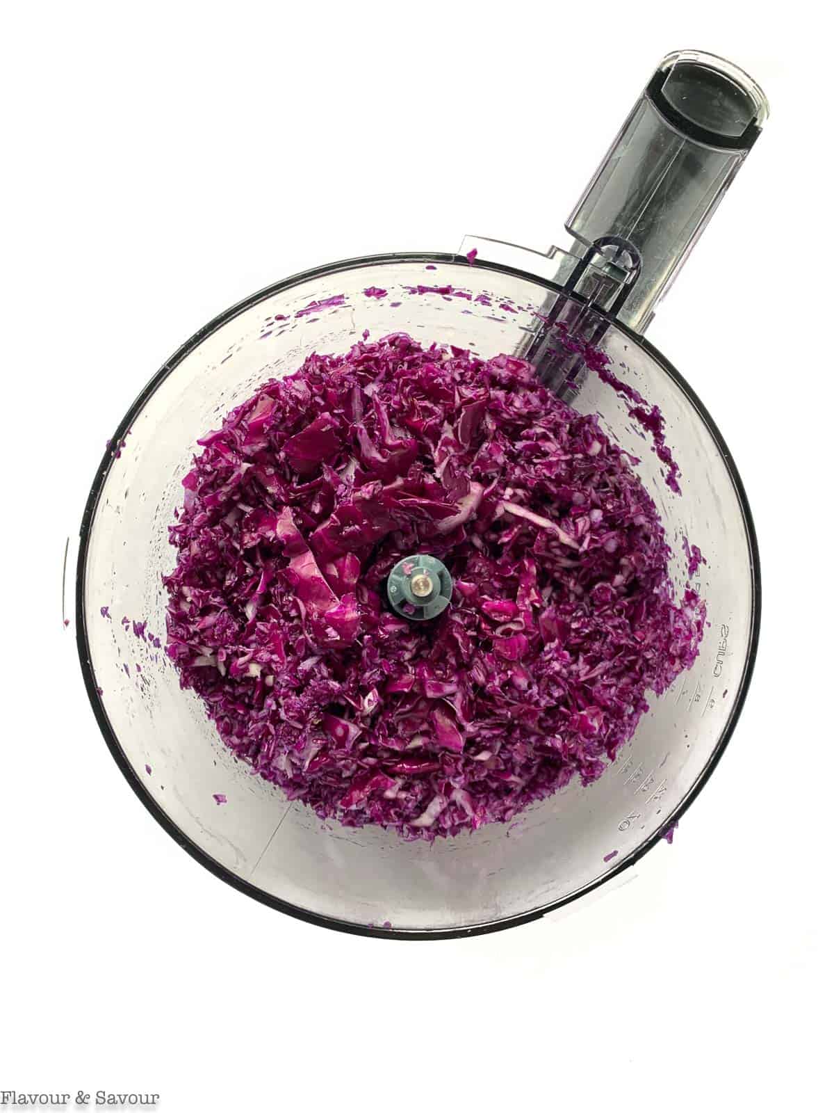 Grated red cabbage in a food processor bowl.