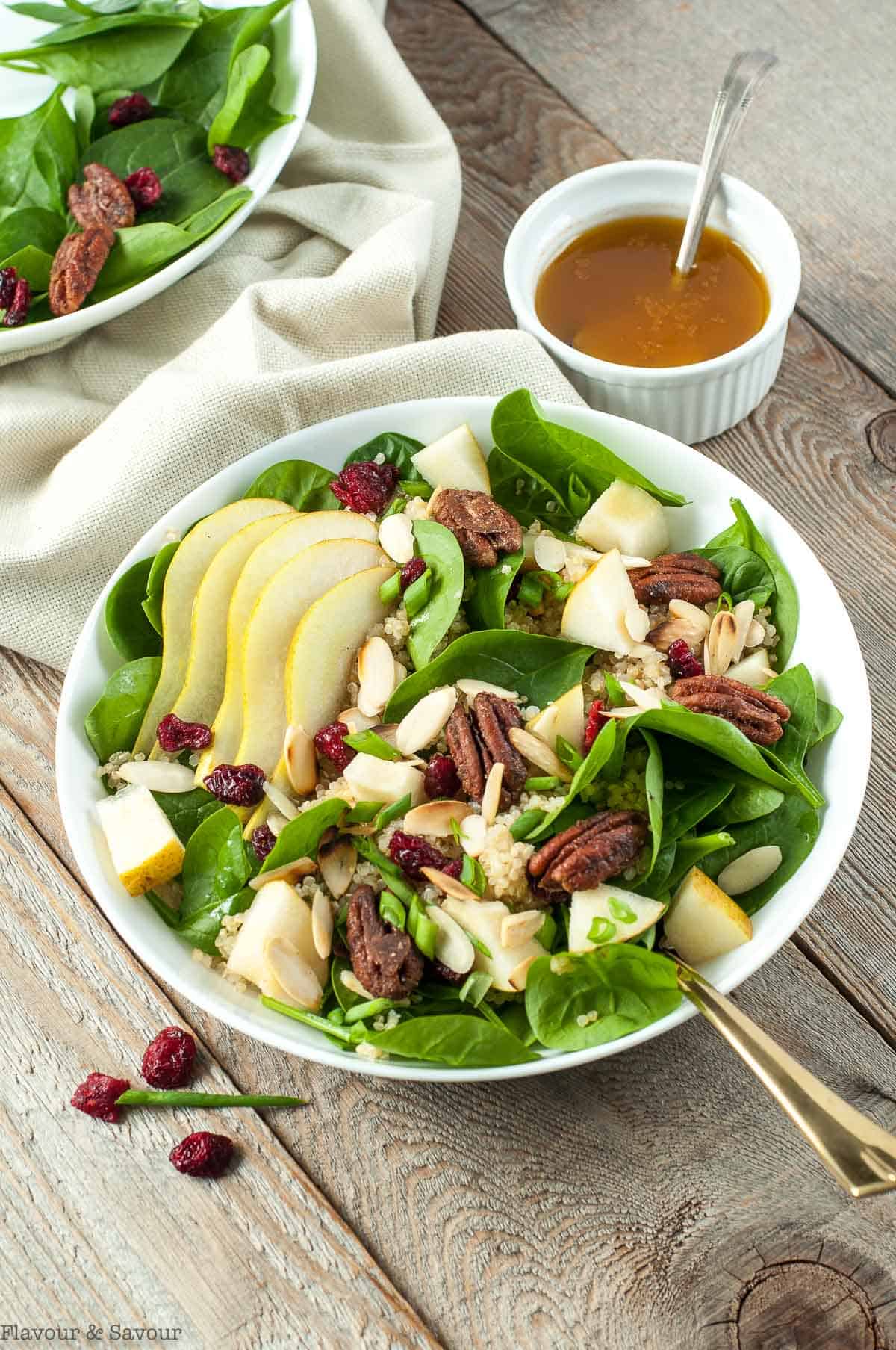 Harvest Quinoa Salad in two bowls with a bowl of dressing