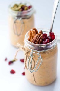 Creamy Pumpkin Pie Overnight Oats topped with pecans and cranberries in a jar