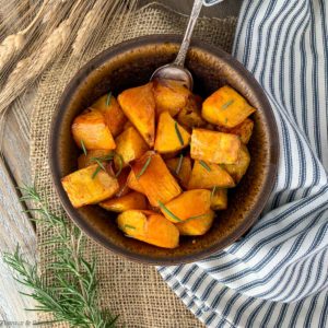 Overhead view of a brown stoneware bowl filled with roasted butternut squash.