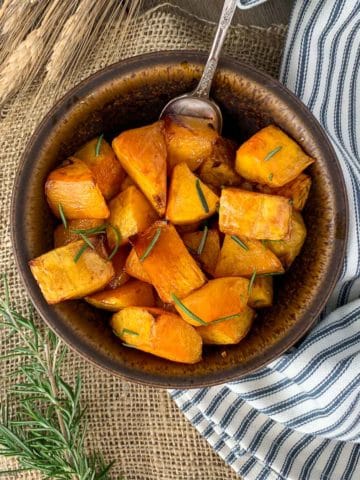 Overhead view of a brown stoneware bowl filled with roasted butternut squash.