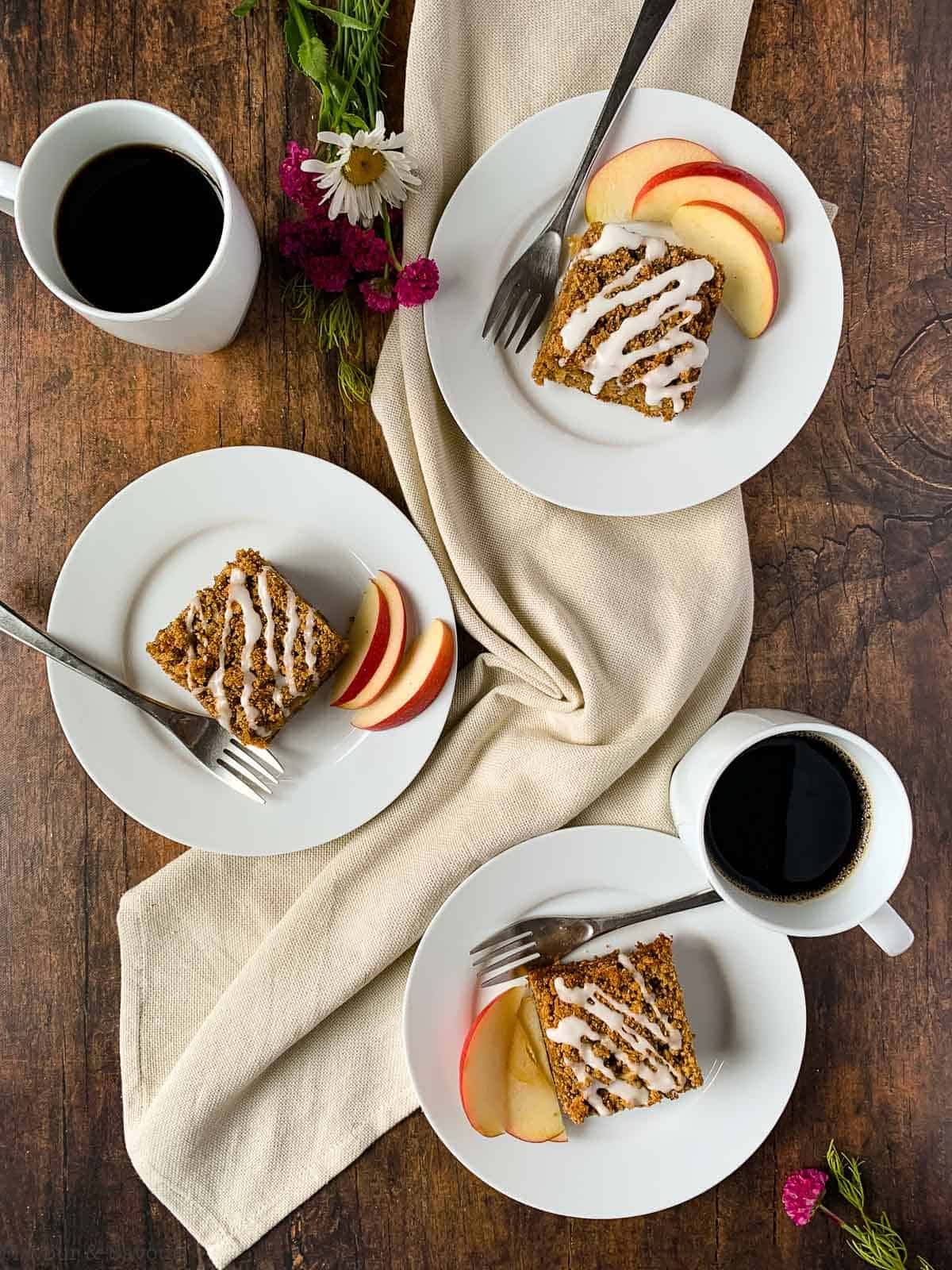 Overhead view of 3 plates of gluten-free apple cinnamon coffee cake with coffee.