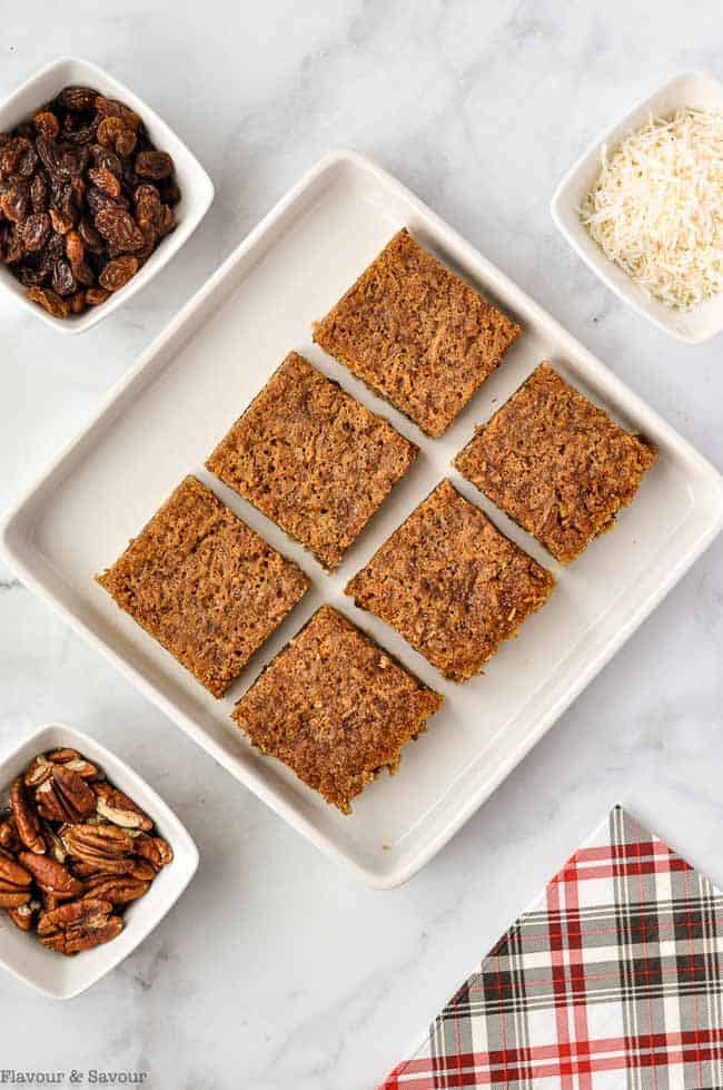 Overhead view of 6 butter tart squares on a square serving plate.