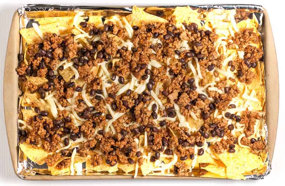 These Loaded Sheet Pan Nachos have it all. Crispy chips, ooey-gooey cheese, spicy chicken, creamy avocado, and lots of crunchy veggies--a perfect combo! |www.flavourandsavour.com