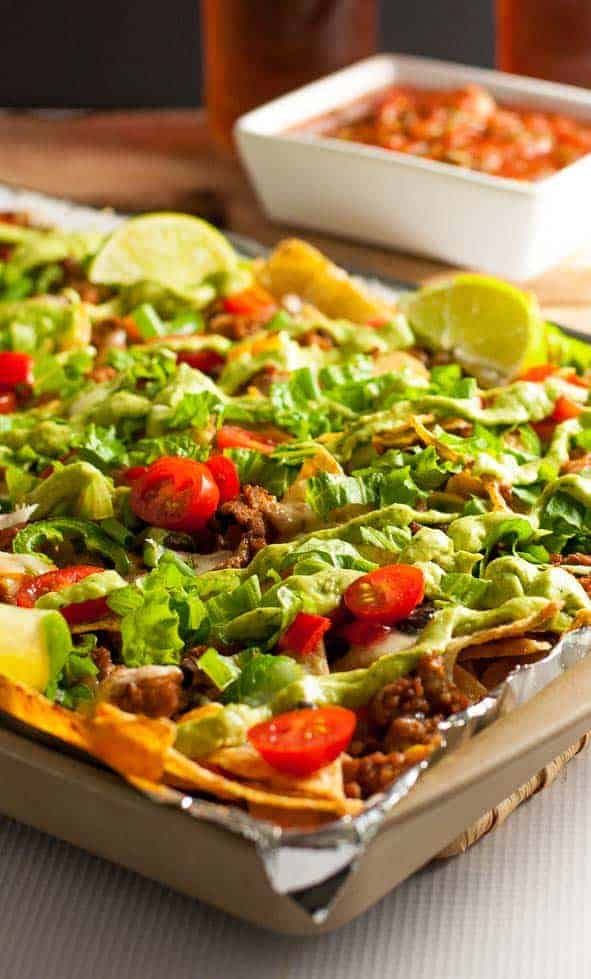 These Loaded Sheet Pan Nachos have it all. Crispy chips, ooey-gooey cheese, spicy chicken, creamy avocado, and lots of crunchy veggies--a perfect combo! |www.flavourandsavour.com
