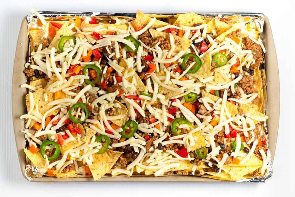 These Loaded Sheet Pan Nachos have it all. Crispy chips, ooey-gooey cheese, spicy chicken, creamy avocado, and lots of crunchy veggies--a perfect combo! |www.flavourandsavour.com