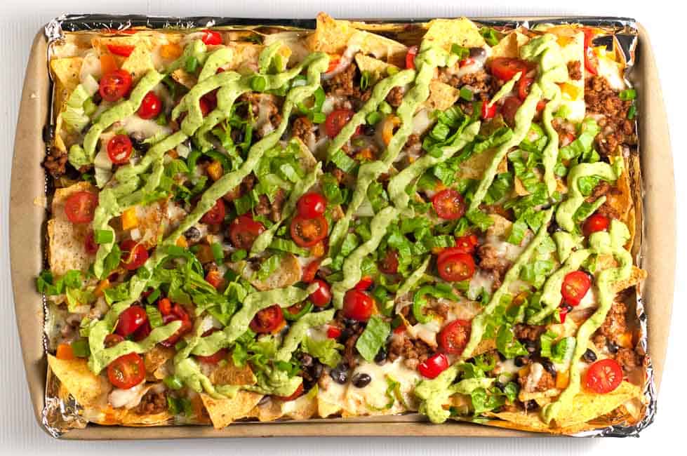 These Loaded Sheet Pan Nachos have it all. Crispy chips, ooey-gooey cheese, spicy chicken, creamy avocado, and lots of crunchy veggies--a perfect combo! |www.flavourandsavour.com