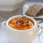 Slow Cooker Sweet Potato Turmeric Soup in a white soup bowl garnished with crispy fried shallots.