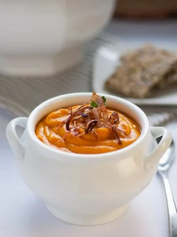 Slow Cooker Sweet Potato Turmeric Soup in a white soup bowl garnished with crispy fried shallots.