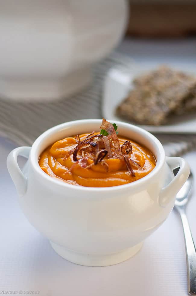 Slow Cooker Sweet Potato Turmeric Soup is a white soup bowl garnished with fried shallots.