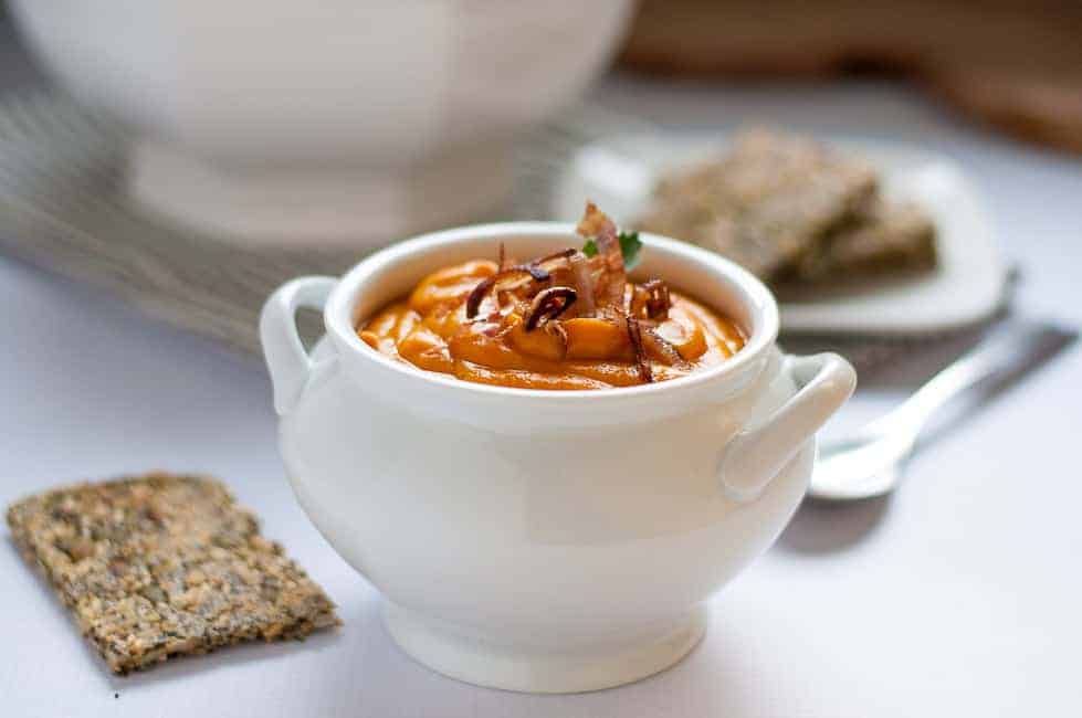 Slow Cooker Sweet Potato Turmeric Soup in a small soup tureen with Super Seedy Snack Crackers