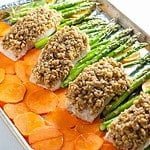 Maple walnut-crusted halibut on a sheet pan with thinly sliced sweet potatoes and asparagus spears.