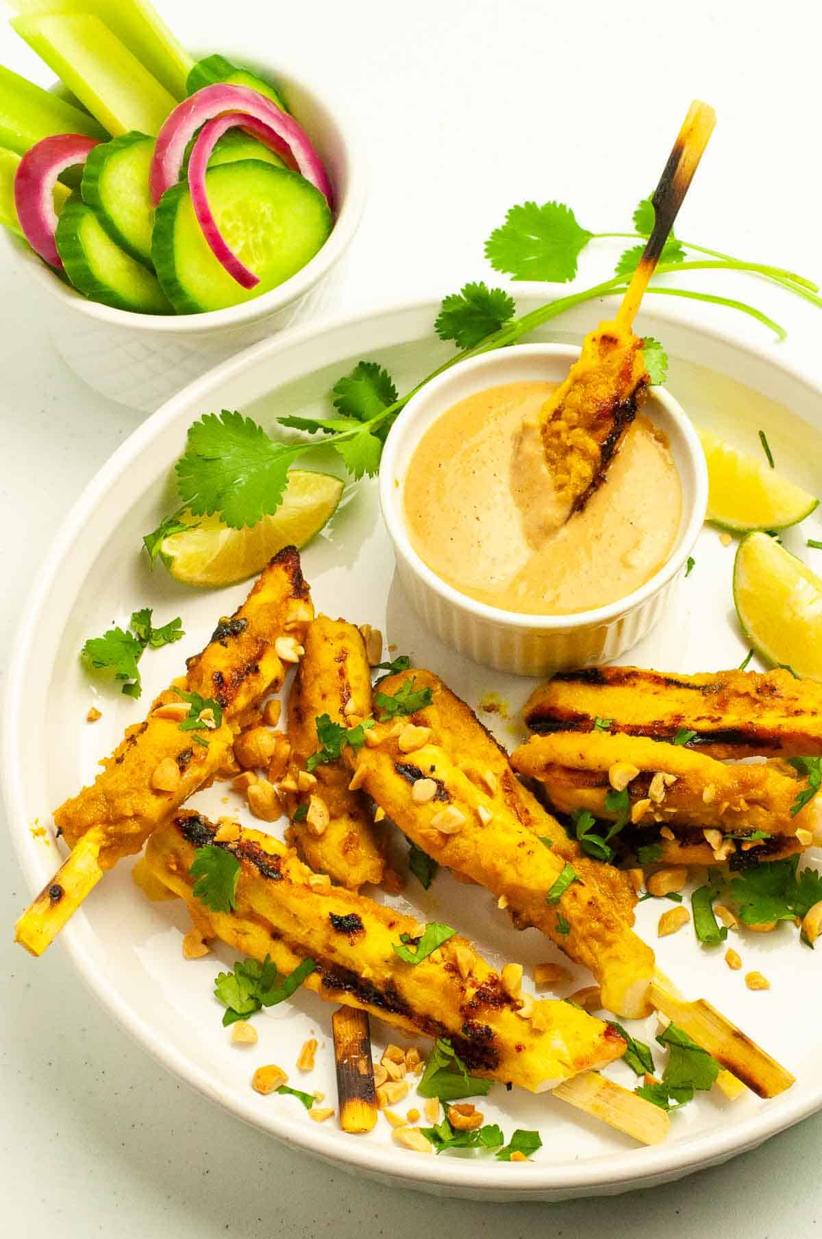 Chicken satay skewers with a bowl of peanut sauce.