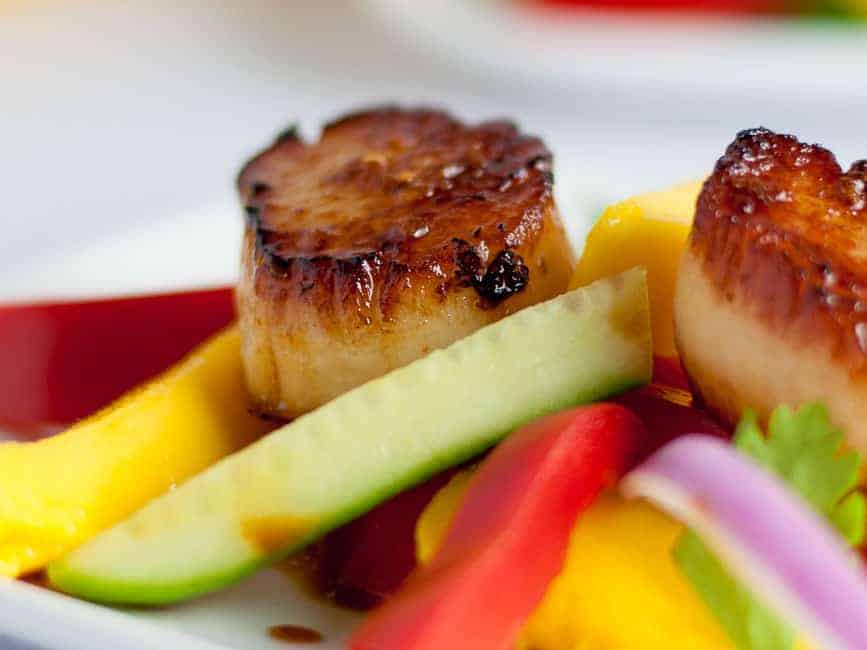 Seared Scallops with Mango Salad. Discover three simple steps to create perfectly seared scallops, and serve them on a colourful salad made with thinly sliced mango, red pepper, cucumber and red onion.