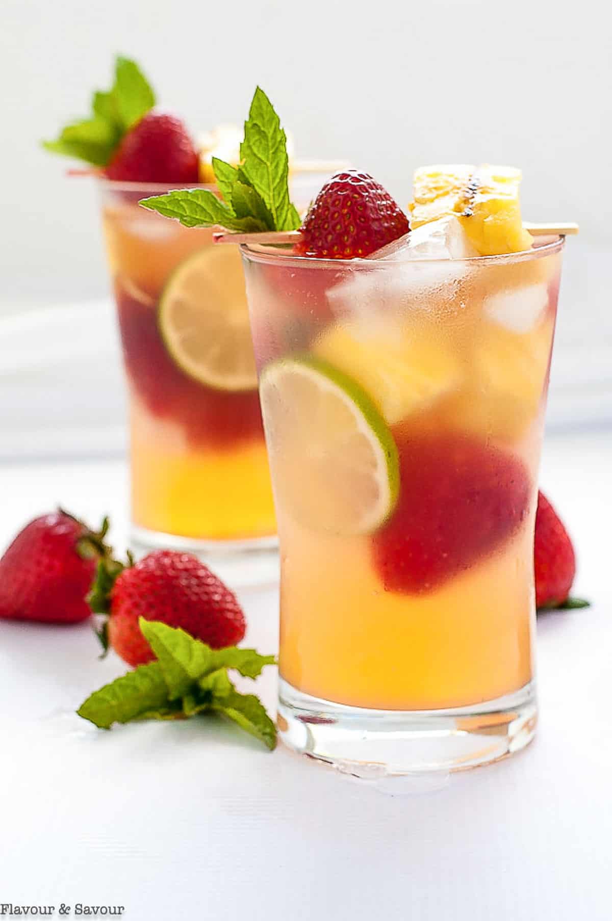 tall glasses of pineapple sangria with strawberries and lime