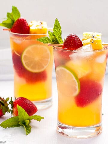 two glasses of grilled pineapple strawberry sangria with fresh berries.