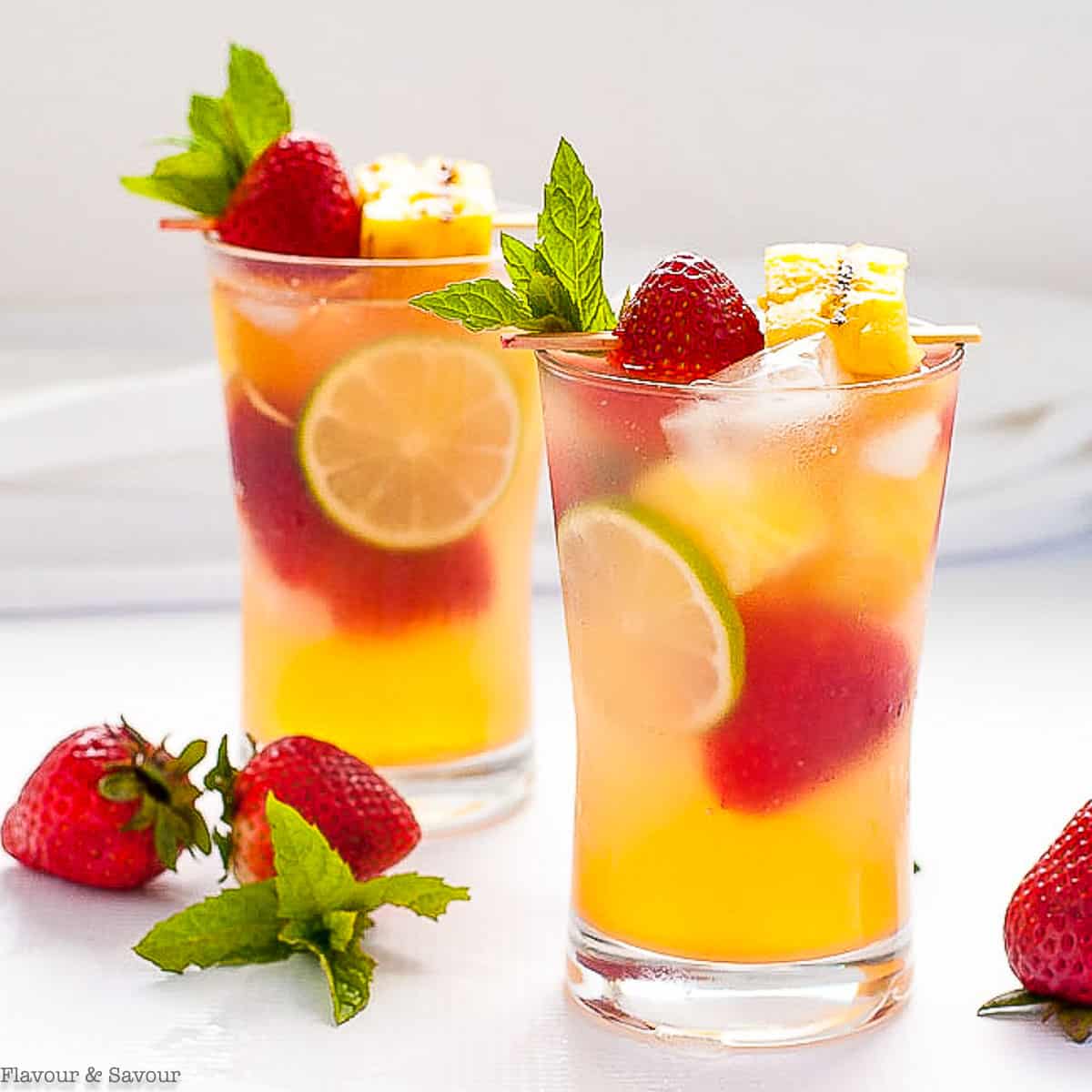 two glasses of grilled pineapple strawberry sangria with fresh berries.