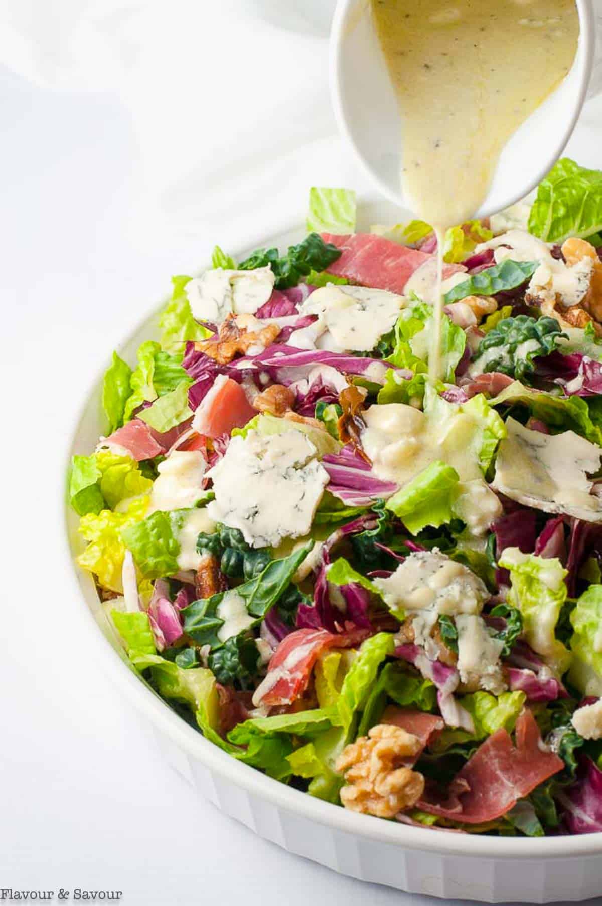 Pouring gorgonzola dressing on Tuscan salad.