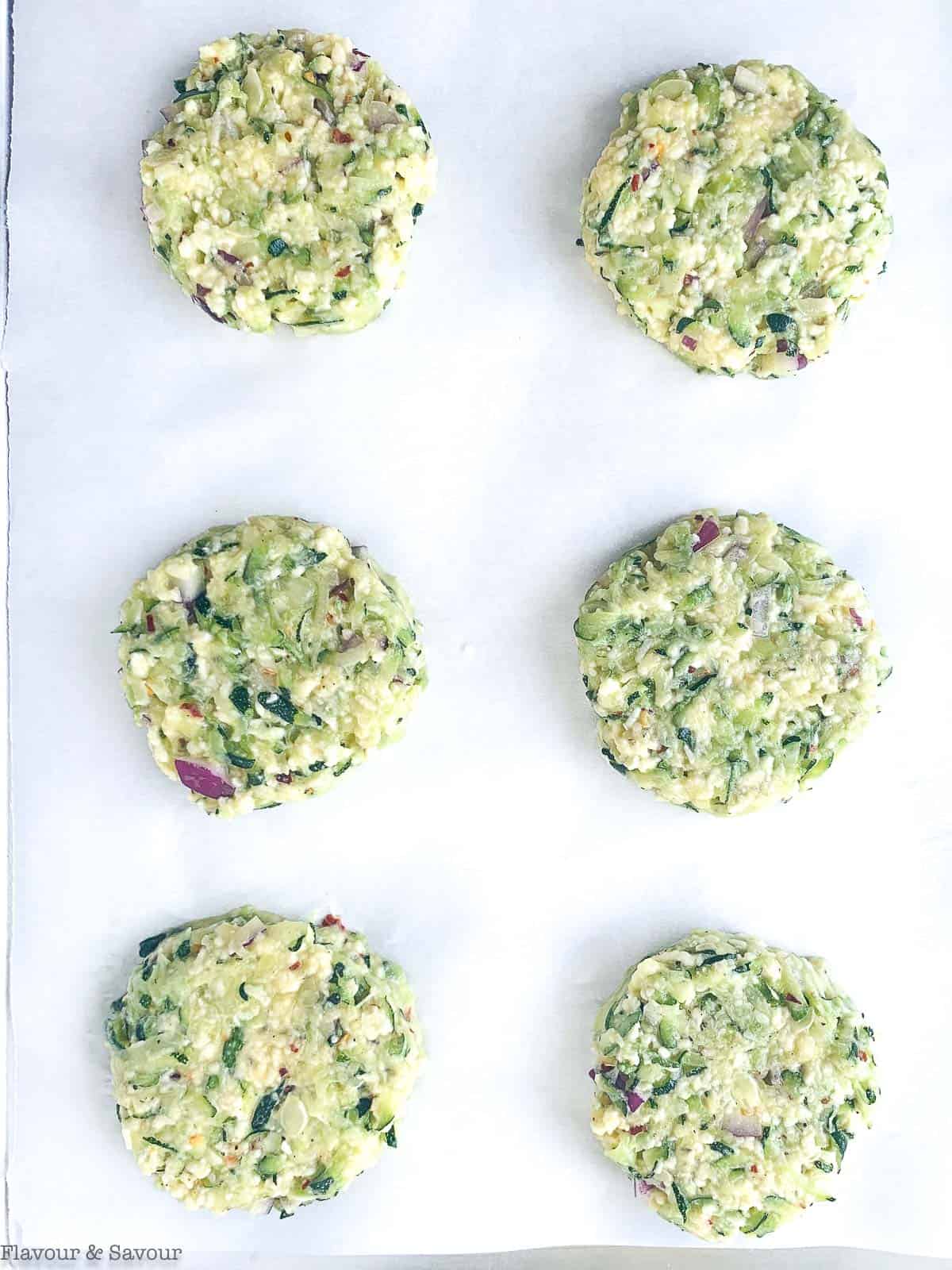 zucchini patties on parchment lined baking sheet ready to bake