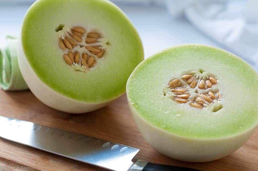 Honeydew Melon sliced in half on a cutting board