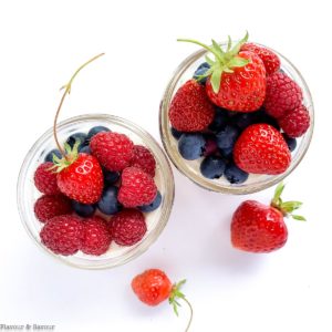 Overhead view of two jars of no bake cheesecake with fresh berries