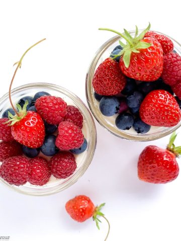 Overhead view of two jars of no bake cheesecake with fresh berries