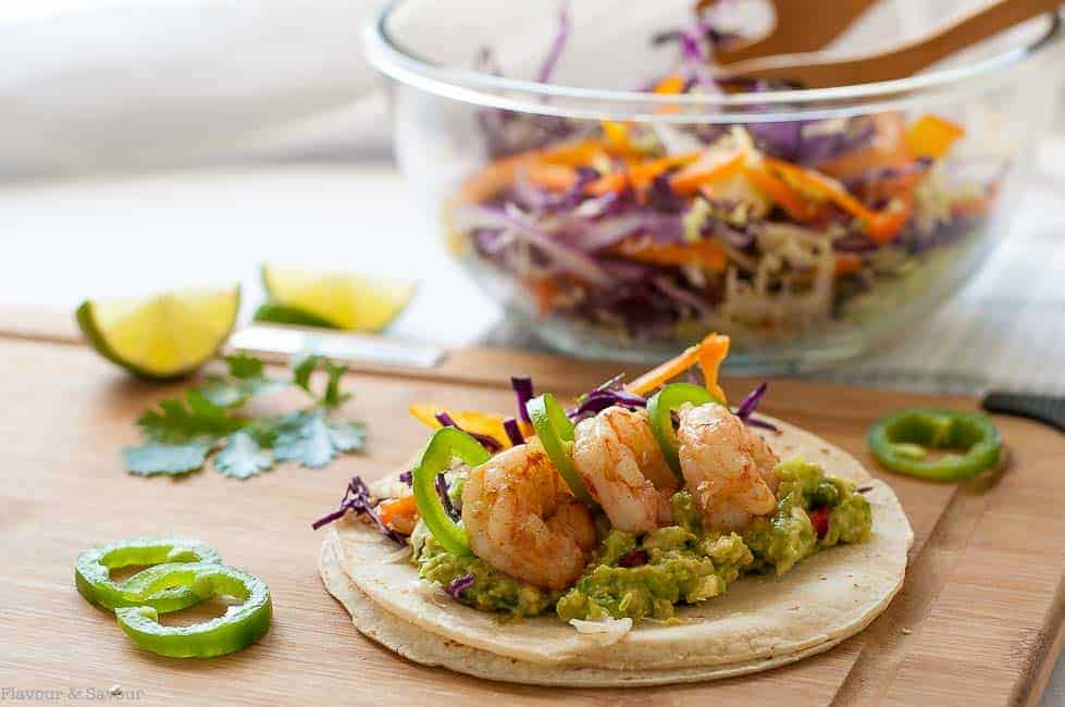 These Shrimp Tacos with Tomatillo Guacamole and crunchy Cilantro Lime Slaw. They're topped with garlicky buttered shrimp, fresh jalapeño and a squeeze of lime.