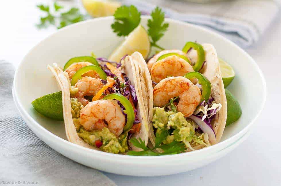 Shrimp Tacos with Tomatillo Guacamole and Cilantro Lime Slaw in a shallow white bowl