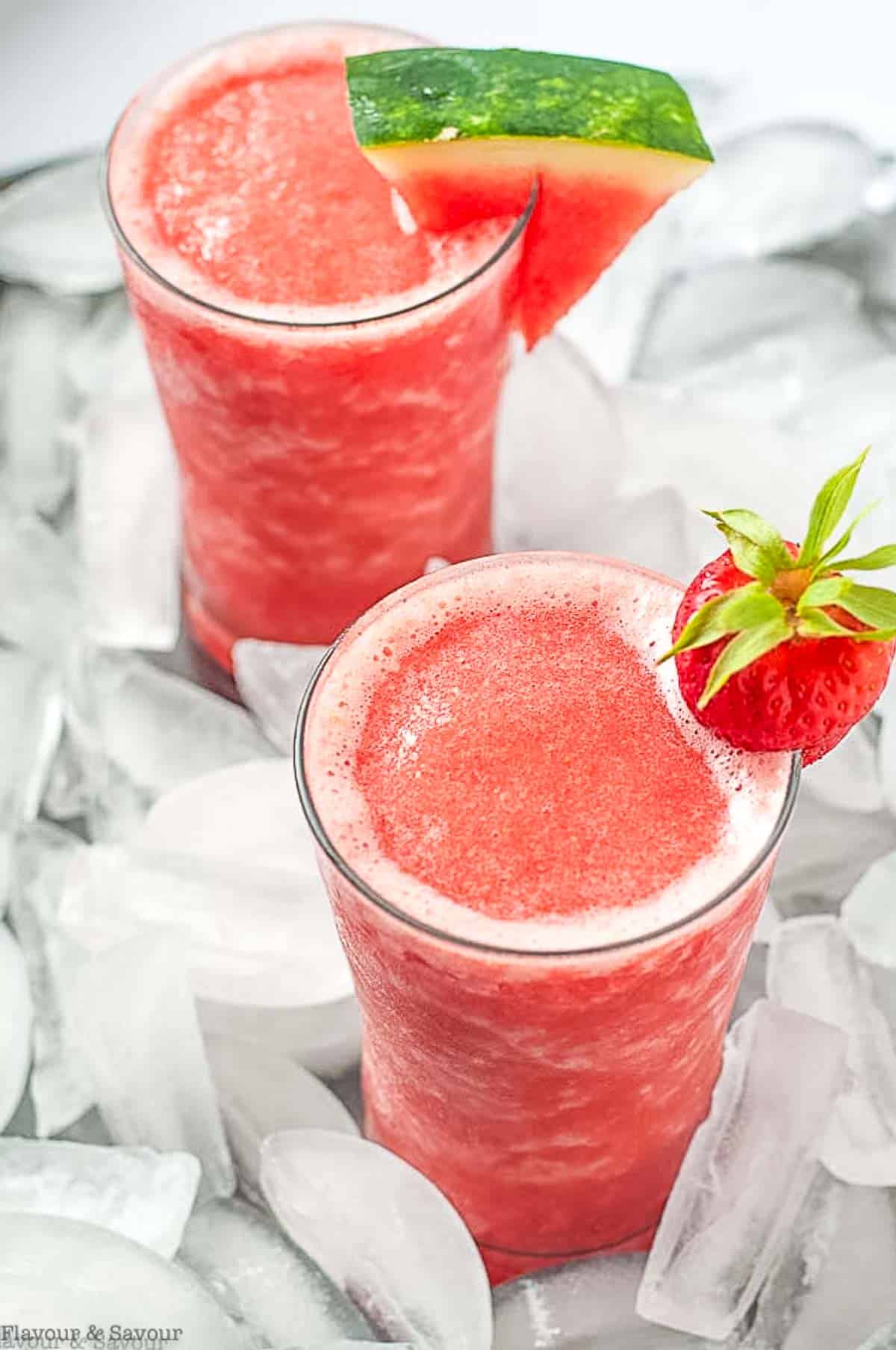 Two glasses of Strawberry Watermelon Sangria Slushie on a bed of ice cubes.