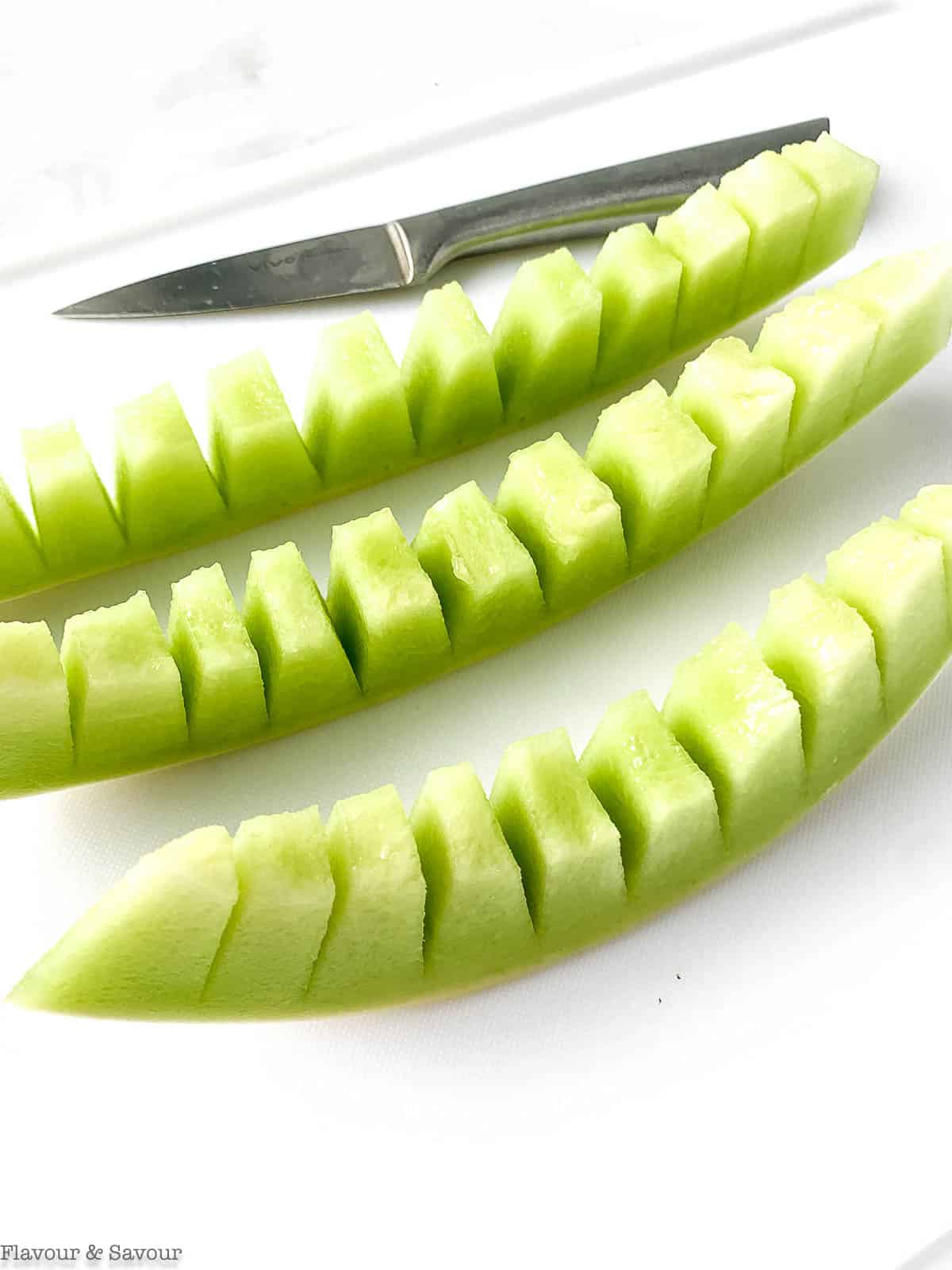 Slicing honeydew melon into strips.