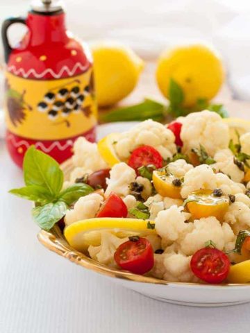 Cauliflower Lemon Basil Salad with toasted capers, fresh basil and cherry tomatoes in a bowl.