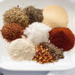 spices and herbs for Cajun seasoning mix in mounds on a white plate