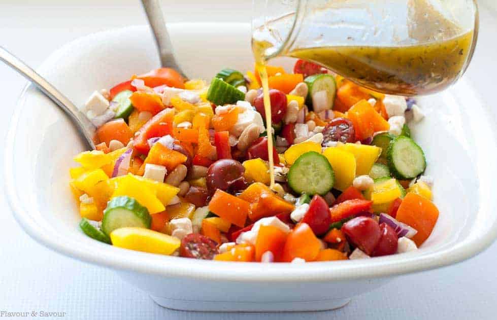 Pouring dressing on Mediterranean Chopped Salad with Cannellini Beans