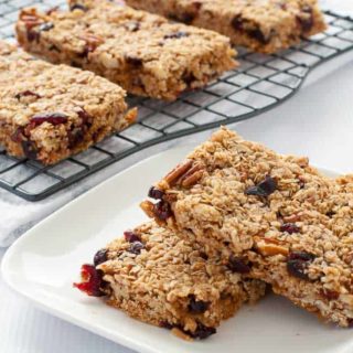 Cranberry Pecan Oat bars on a cooling rack and stacked on a plate.