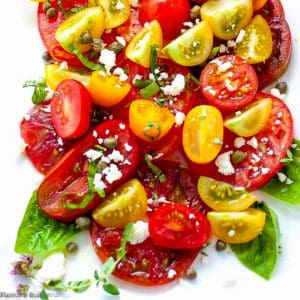 Overhead view of heirloom tomatoes arranged on a platter with feta cheese