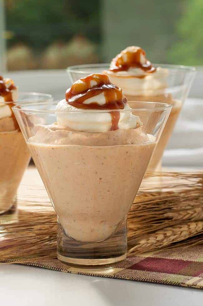 Greek Yogurt Pumpkin Cheesecake Mouse in dessert cups with whipped cream and caramel sauce topping