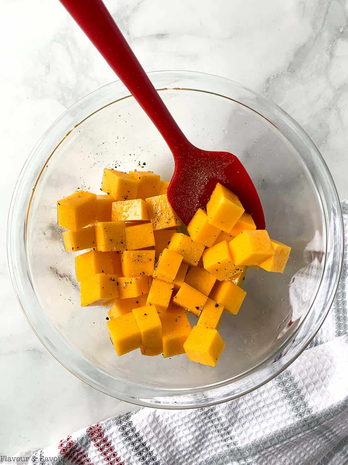 Cubes of butternut squash in a mixing bowl with oil and seasonings.