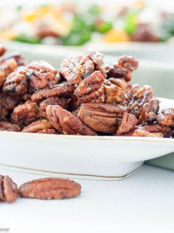 A dish piled high with caramel spiced pecans.